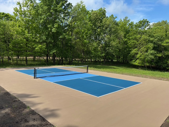 resurfaced multiple blue colored outdoor pickle ball court with a gray boundary