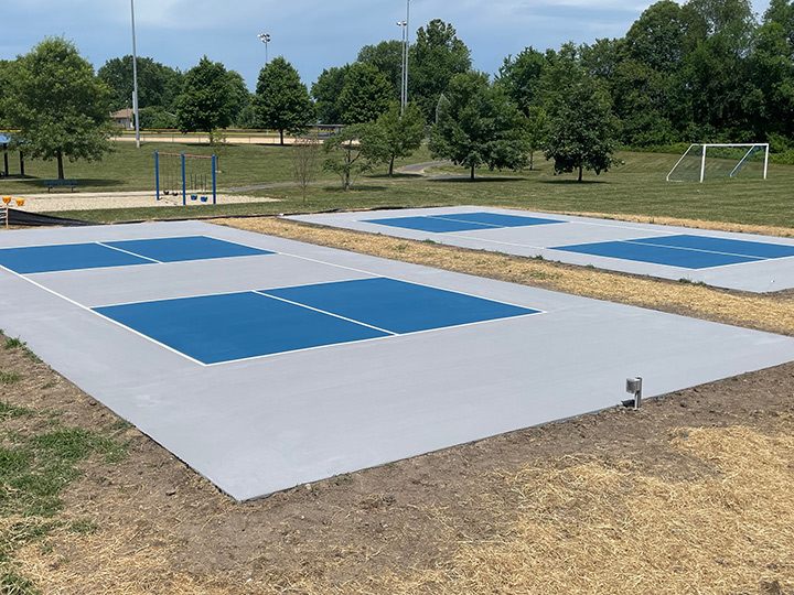 a resurfaced pickle ball with a soccer field in the background